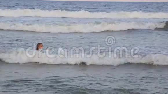 一个冲浪女孩在漂浮在绿色蓝色海洋的冲浪板上看日落视频的预览图