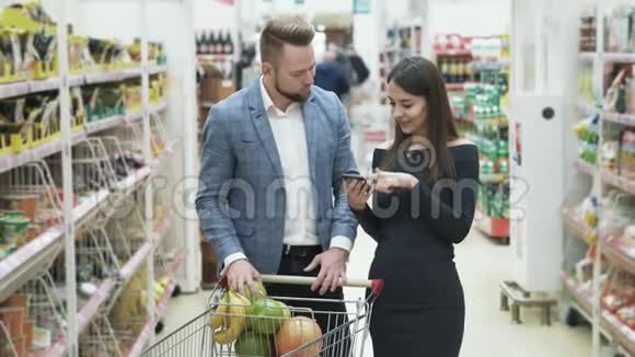 女人用智能手机检查产品清单男人选择水果在超市闻视频的预览图