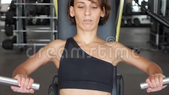 运动女性的初学者第一次使用手臂肌肉模拟器健身房里的新手视频的预览图