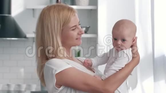母亲手中的新生儿幸福的父母拥抱小女孩在厨房里看镜头视频的预览图