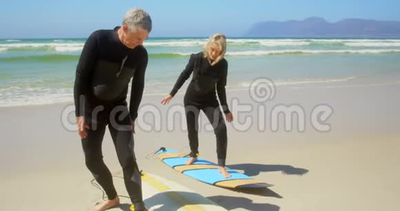 活跃的高加索夫妇在海滩上冲浪的正面景色视频的预览图