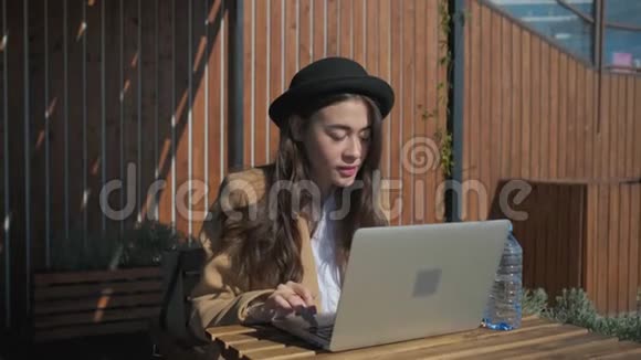 快乐的女士坐在咖啡馆里露天的笔记本电脑里读留言视频的预览图