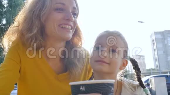 夏天穿着黄色衬衫的美丽年轻母亲和她的小女儿一起放松的特写照片视频的预览图