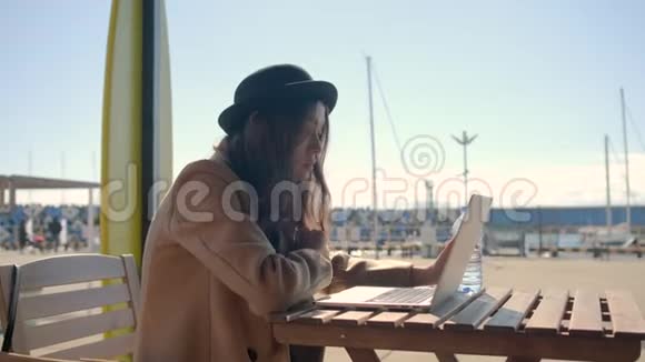 浪漫的女人独自坐在笔记本电脑前在户外的屏幕上观看视频的预览图
