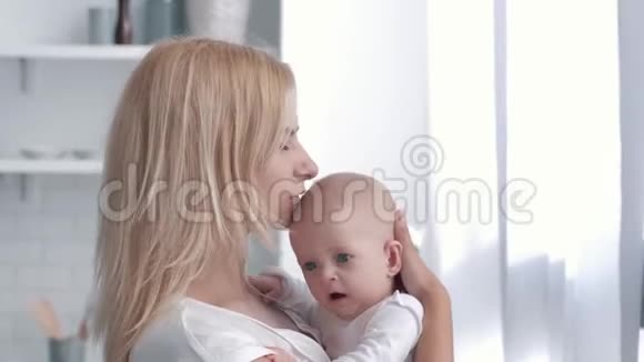母爱年轻的父母温柔地抱着他的新生女孩然后拥抱和亲吻厨房视频的预览图