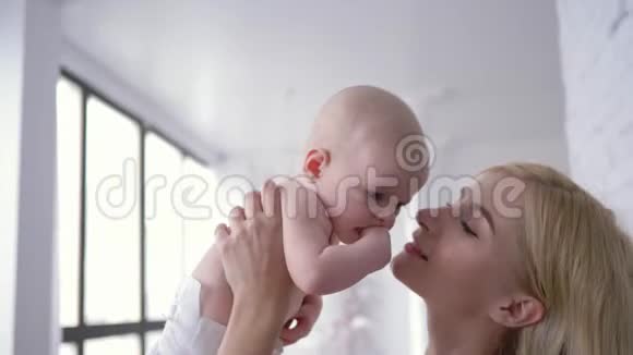 母亲轻轻地吻着一个新生的婴儿幸福的年轻女子抱着一个小女孩看着相机的画像视频的预览图
