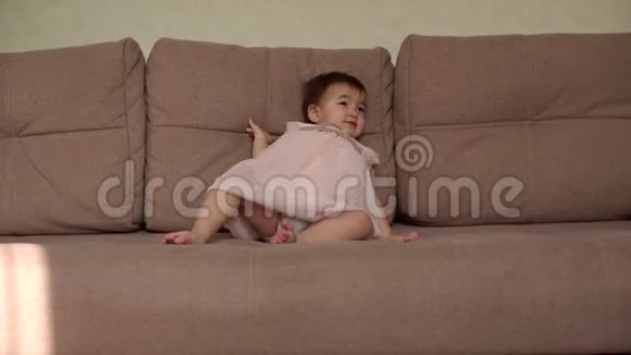 小可爱的女婴慢慢地从柔软的沙发上滑到地板上视频的预览图