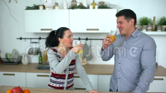 这对夫妇在厨房里喝橙汁健康的生活方式慢动作视频的预览图