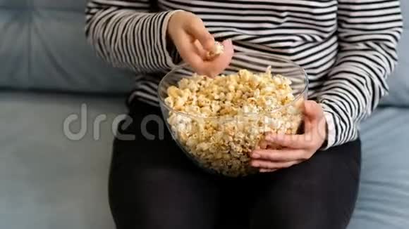 女手从纸桶特写中摘爆米花接近在电影院吃爆米花的女人电影食品概念视频的预览图