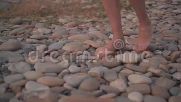 雌性晒黑的双腿赤脚行走在岩石海岸上女孩不确定跌跌撞撞视频的预览图