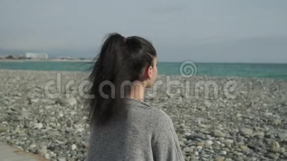 早晨年轻的女士坐在海岸边注视着平静的海面视频的预览图