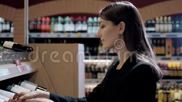 年轻漂亮的女人在超市买酒布鲁内特在酒精店视频的预览图