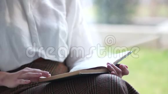 特写女郎坐在窗台上看一本旧书快乐的女人视频的预览图