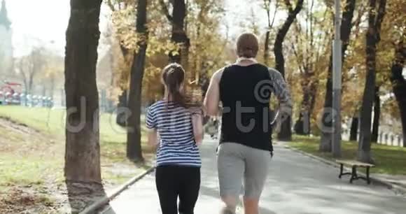 年轻人和女孩在锻炼健身夫妇一起在阳光公园跑步男子和妇女一起参加体育训练视频的预览图