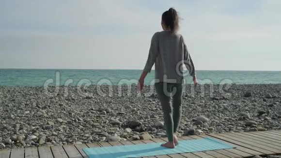 布鲁内特女士伸出双手站在海边的一条腿上视频的预览图