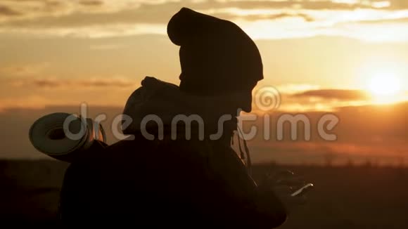 年轻旅游女性的剪影使用电话与戏剧性的日落天空背景一直联系在一起视频的预览图