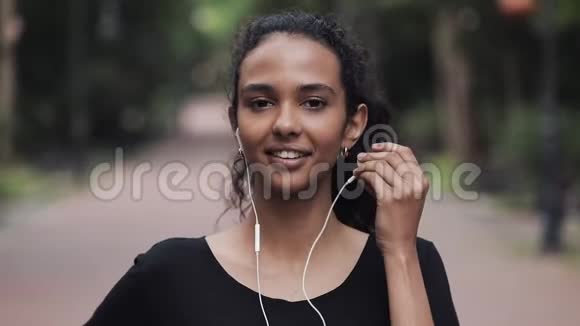 一幅年轻美丽的女子戴着耳机站在公园的特写镜头健康生活方式理念视频的预览图