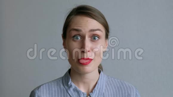 一个美丽的女孩傻瓜周围并显示她的舌头背景白墙视频的预览图