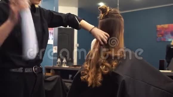 理发师用发胶在沙龙的客户头发上头发造型理发店做发型师美发师视频的预览图