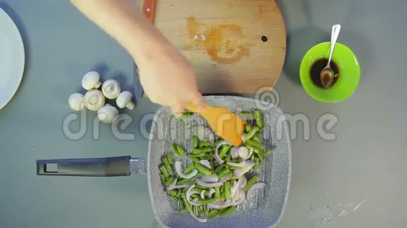 一个女人手正用木铲搅拌洋葱和青豆视频的预览图