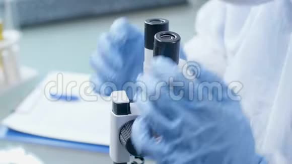 近距离拍摄实验室技术人员在看显微镜时做笔记视频的预览图