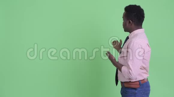 一位严肃的年轻非洲商人向后面展示了一些东西视频的预览图