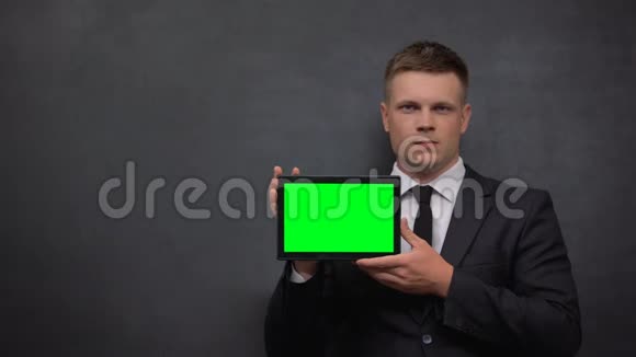 穿着西装的严肃男人带绿色屏幕的平板电脑贸易市场分析视频的预览图