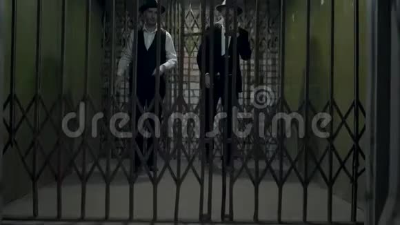 两个穿着正式西装戴着fedora帽子的歹徒打开了金属锻造的大门视频的预览图