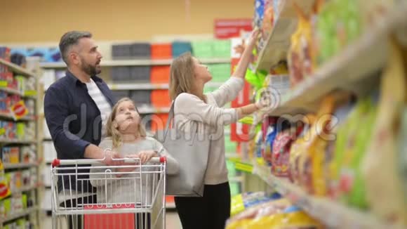 在超市三口幸福家庭手牵手走过商店的新鲜农产品部分父亲视频的预览图