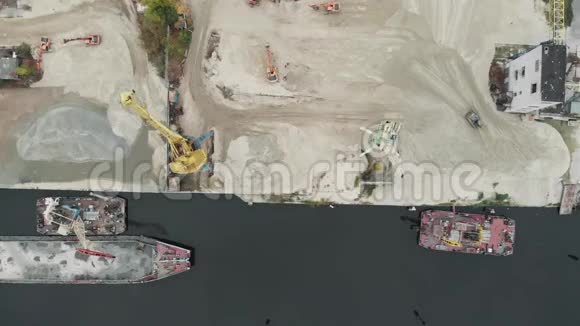 河岸上的港口起重机产生沙子河岸上有桶的港口起重机用卡车和挖掘机抽取沙子视频的预览图