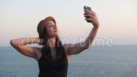 女人在日落时分用手机自拍微笑着享受大自然视频的预览图