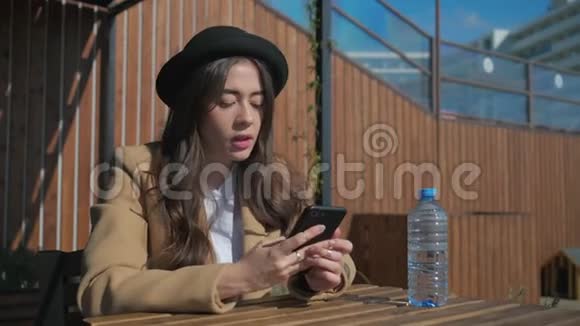 阳光明媚的一天一位快乐的黑发女士坐在公园里用手机聊天视频的预览图