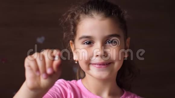 一个没有牙齿的女孩的肖像显示一颗撕裂的牙齿伸出手进入相机转移重点视频的预览图