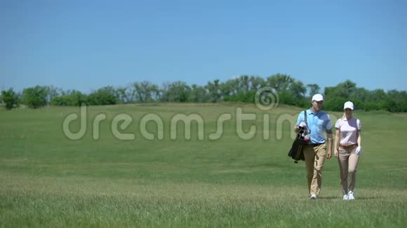 高尔夫球手与球杆包的配对在球场上交流在游戏后散步视频的预览图