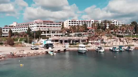 塞浦路斯酒店餐厅和白船在珊瑚湾海滩海上码头酒店和游船在海附近的鸟瞰图视频的预览图