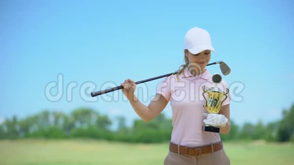拥有球杆和金杯的快乐女高尔夫球手相机微笑运动胜利视频的预览图