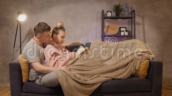 一个年轻的女人和一个男人坐在沙发上看书一男一女快乐视频的预览图