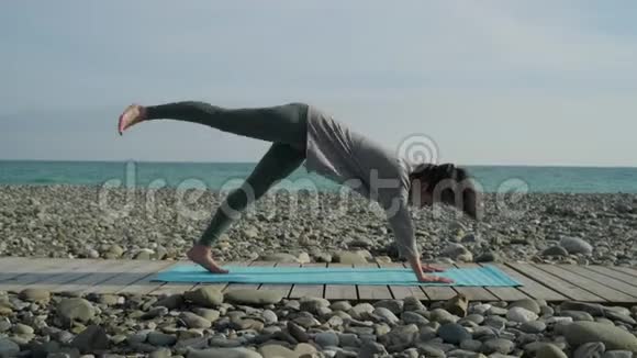 女人靠在地板上双手抬起腿在外面做瑜伽视频的预览图