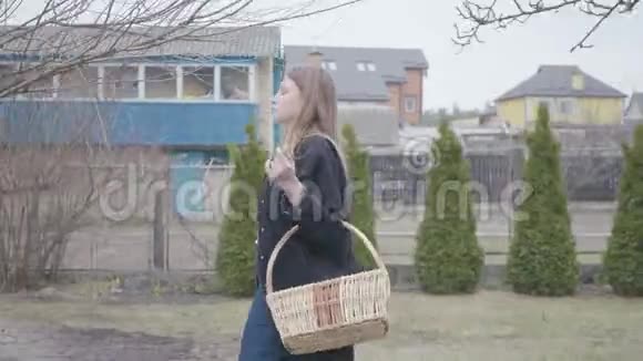 可爱的年轻女子走着手里拿着柳条篮子核桃穿休闲服装的有魅力的艺术家视频的预览图