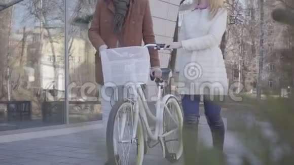 无法辨认的女人穿着温暖的白色夹克高个子男人穿着棕色外套骑着自行车走在街上休闲视频的预览图