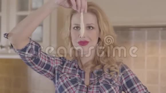 年轻的金发女人涂着红色口红长发手里拿着一块面团看着它就像看着恶心的东西一样视频的预览图
