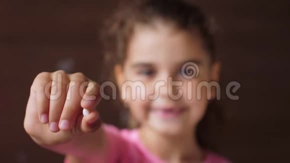一个没有牙齿的女孩的肖像显示一颗撕裂的牙齿伸出手进入相机转移重点视频的预览图