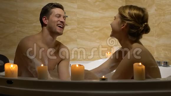快乐的情侣在洗澡浪漫的夜晚水疗中心欢笑享受乐趣视频的预览图