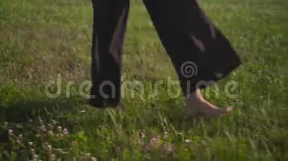 女性腿特写商务女性穿黑色裤子光着脚在草坪上玩得开心自由视频的预览图