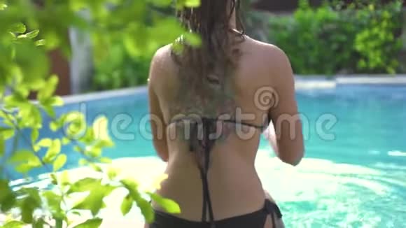 穿比基尼的年轻女子在避暑胜地的游泳池里泼水后景美丽的女人有着五颜六色的纹身视频的预览图