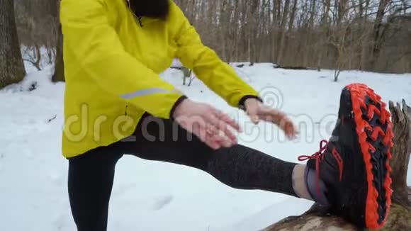 在冬季森林里跑步前运动员伸展双腿的弧线射击视频的预览图