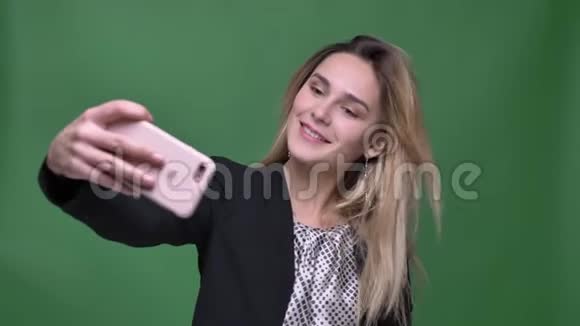 年轻迷人的潮人白种人女性在手机上自拍的特写镜头背景与绿色隔离视频的预览图