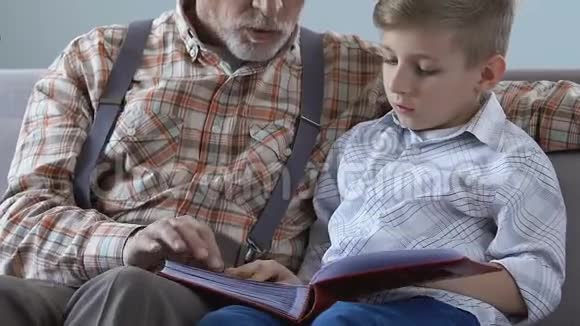 老人展示相册照片孙子讲述生活故事家庭亲密视频的预览图