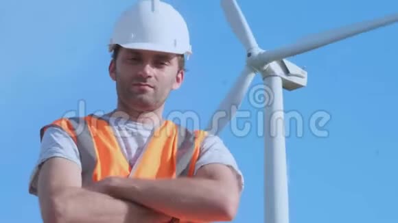 端口近景拍摄的成年工程师穿着橙色背心和白色安全帽背景上有风力涡轮机视频的预览图