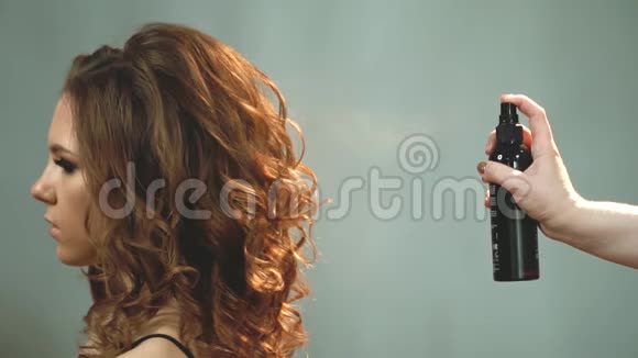 女人正在从瓶子里喷上一层清漆涂在一个漂亮女孩头发上视频的预览图